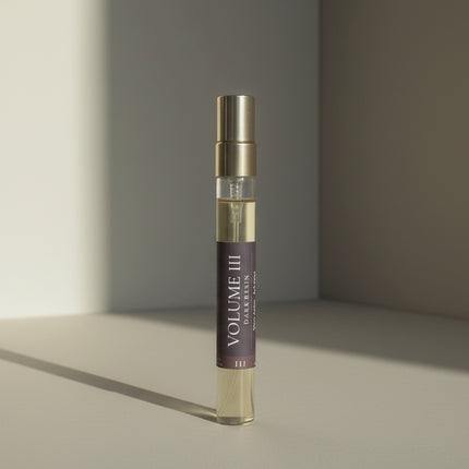 Cologne bottle labeled 'Volume III' on a neutral background